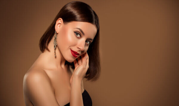 Studio portrait of bare shoulders stunning woman touching her cheekbone standing profile showing cosmetic night visage