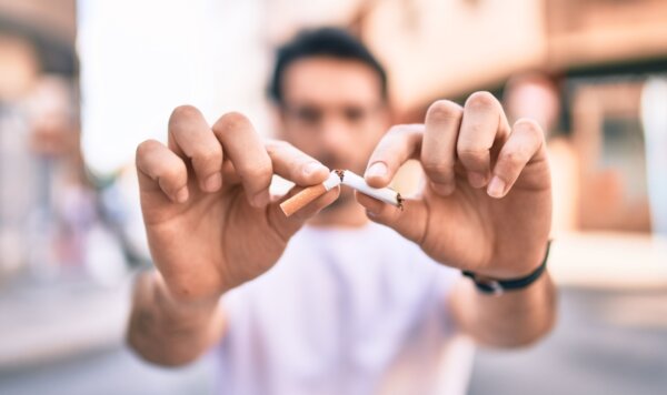 Νεαρός άνδρας σπάει ένα τσιγάρο στα 2, ως ένδειξη της διακοπής του καπνίσματος