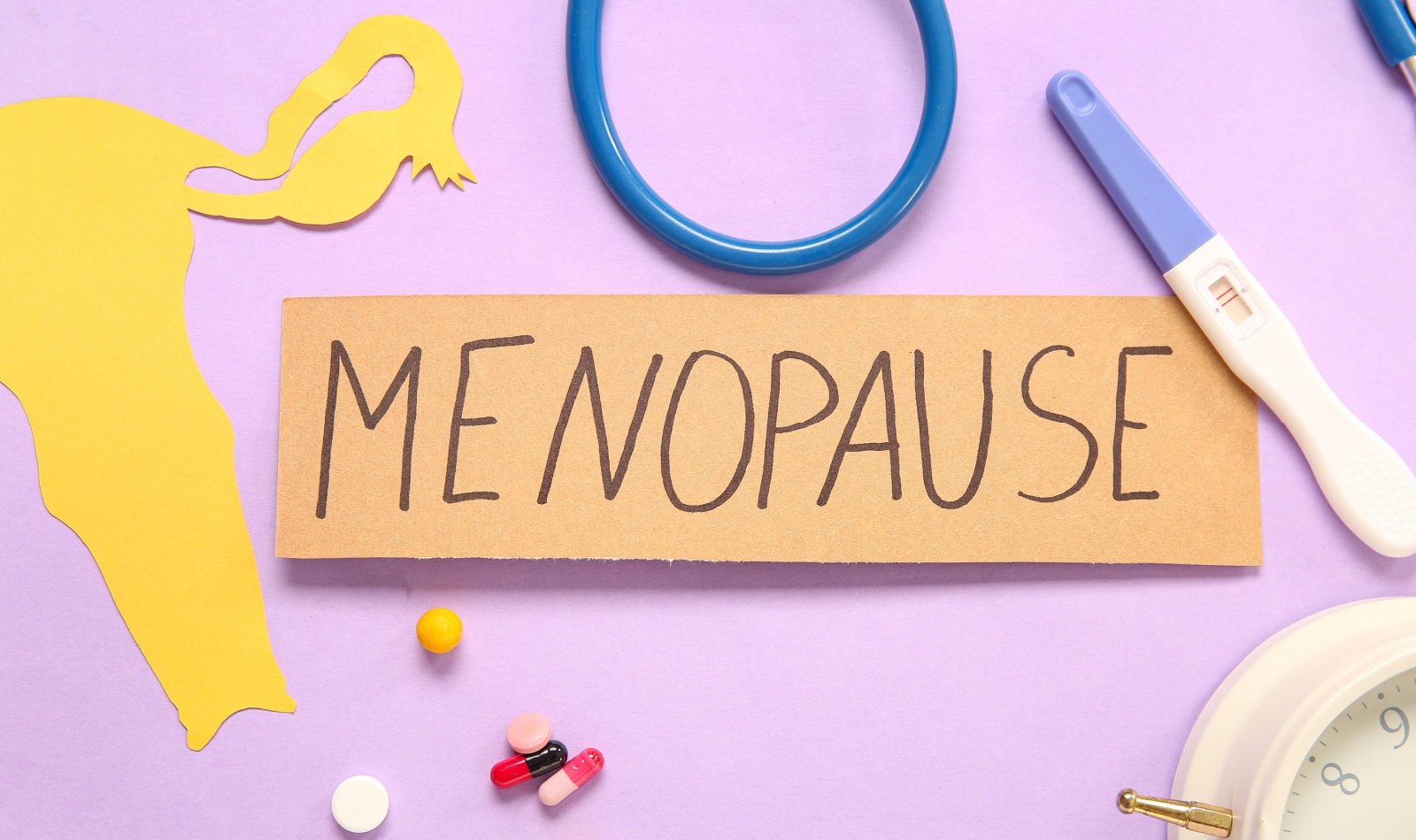 Word MENOPAUSE with pills, paper uterus and pregnancy test on pink background, closeup