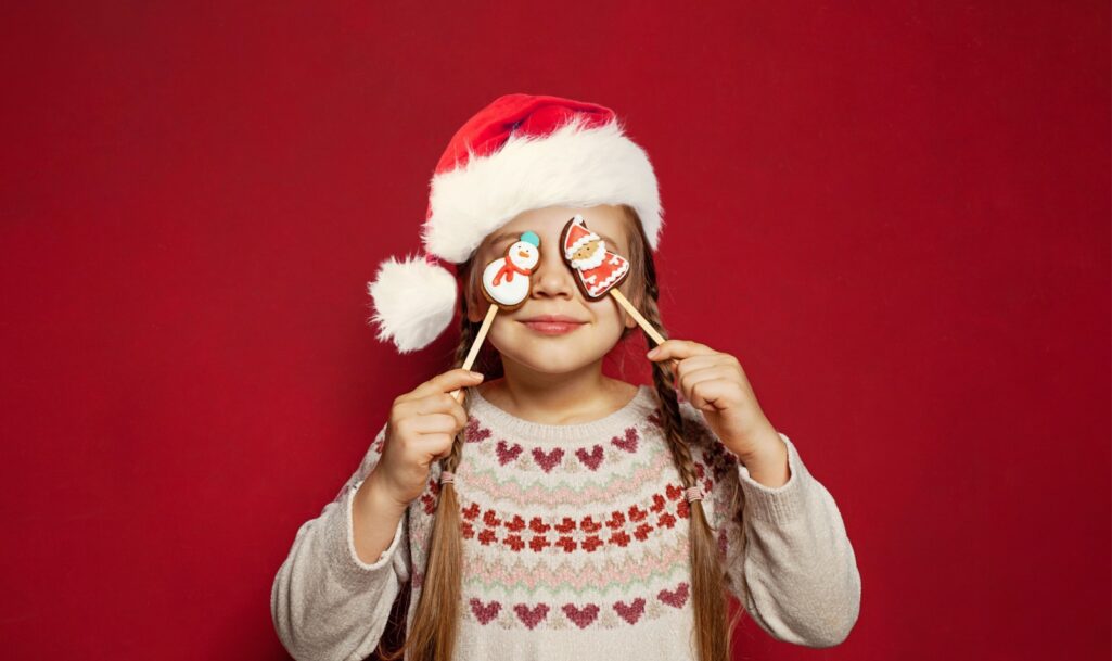 Christmas kid. Adorable little girl and gingerbread cookie Snowman and Santa Claus on red, Xmas concept