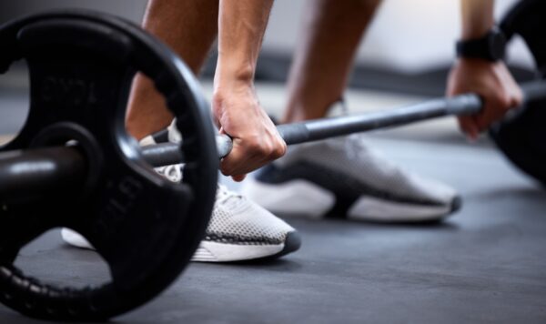 Barbell, fitness and strong hands of man in bodybuilder training for muscle power, legs challenge and workout.