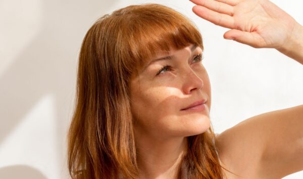 Portrait of caucasian middle aged woman close her face by hand hiding from sunlight on white background